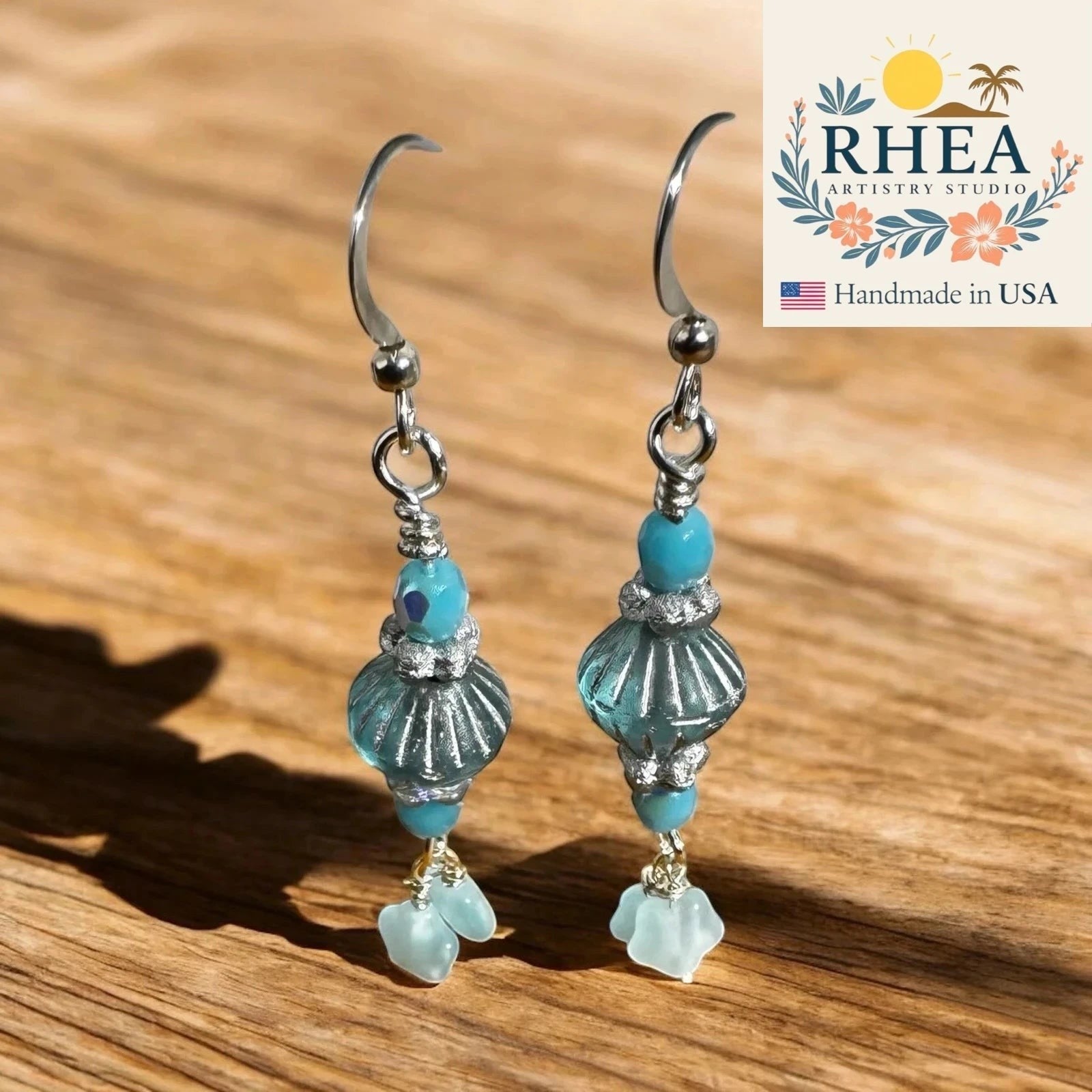 Rhea Artistry Studio aqua and seafoam Czech glass drop earrings with petite floral star accents, silver-toned findings, and fish hook earwires.