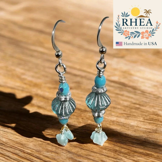 Rhea Artistry Studio aqua and seafoam Czech glass drop earrings with petite floral star accents, silver-toned findings, and fish hook earwires.