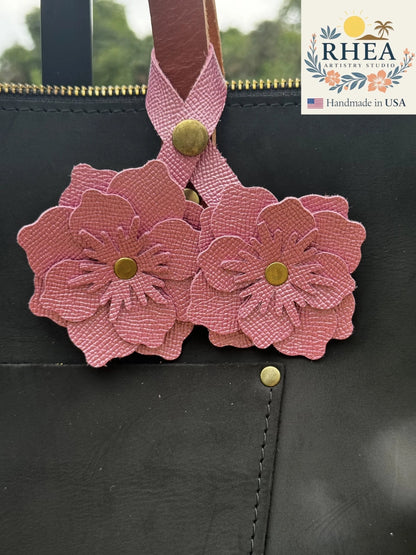 Rhea Artistry Studio Barbie Pink double leather flower charm with brass rivets, attached to a black leather bag.
