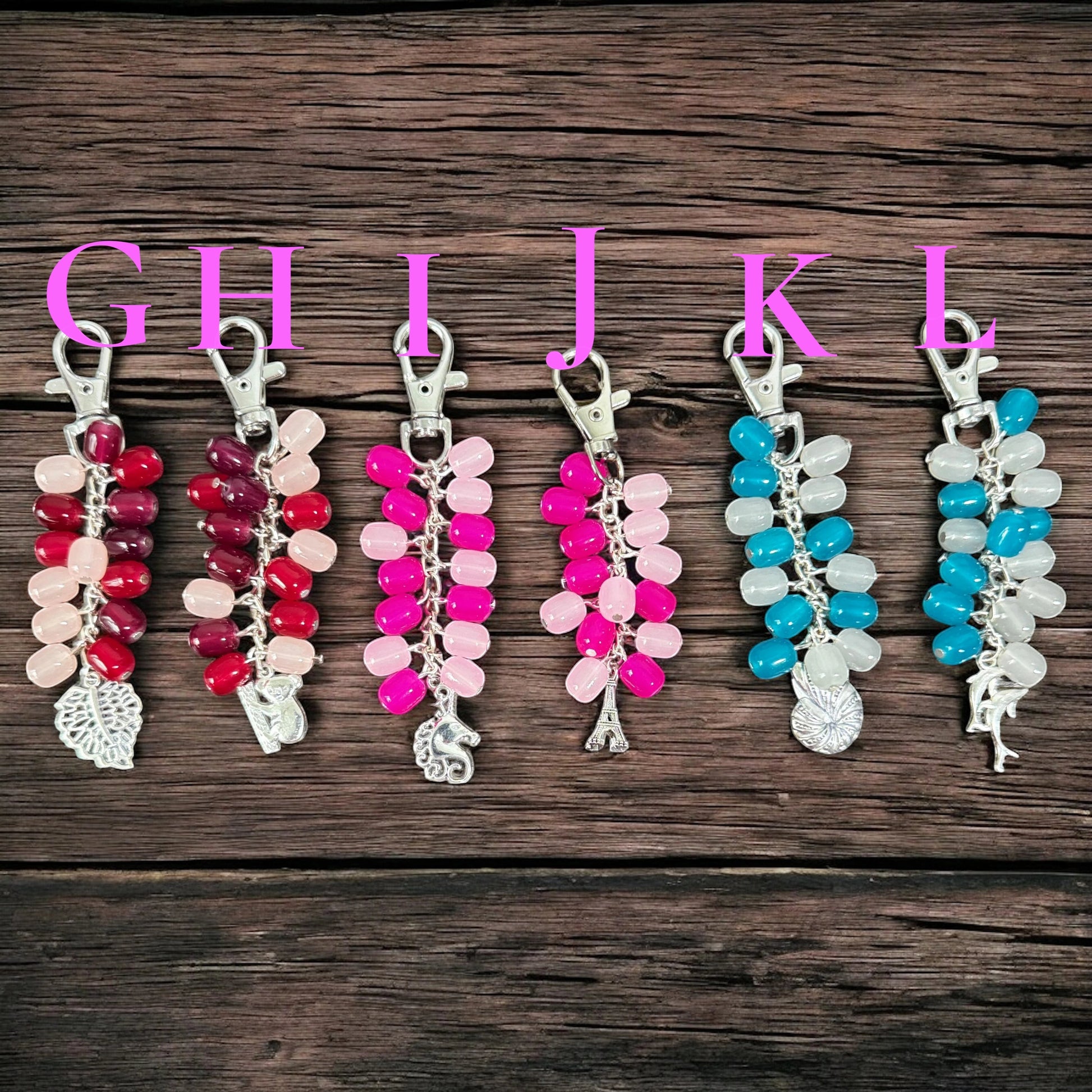 Rhea Artistry Studio handmade beaded keychains in red, pink, blue, and white. Features glass beads and silver-tone charms.