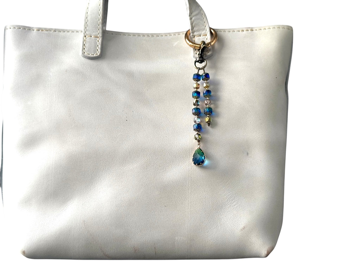 Rhea Artistry Studio elegant beaded keychain with blue teardrop pendant and brass accents, attached to a white tote bag.