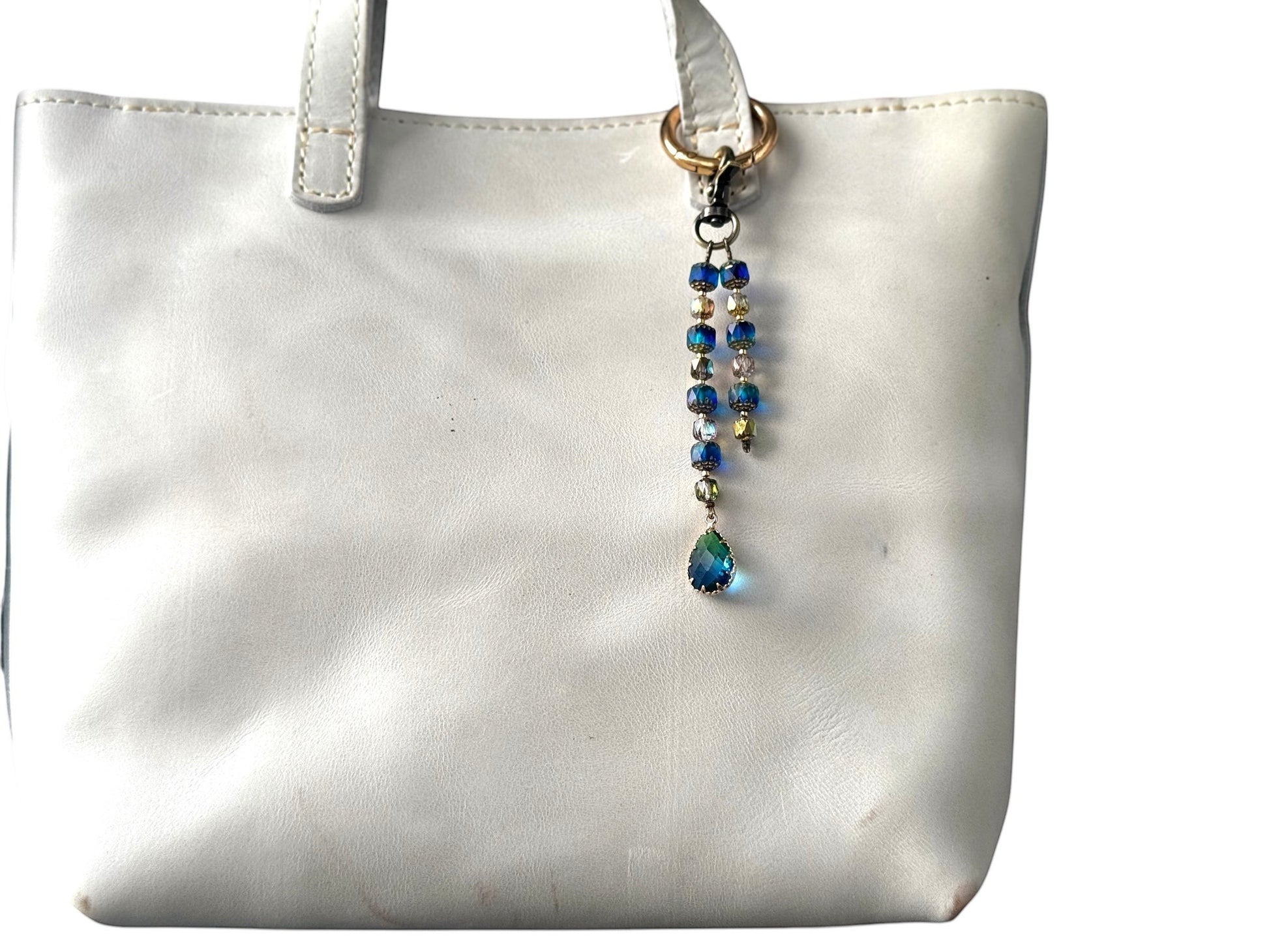 Rhea Artistry Studio elegant beaded keychain with blue teardrop pendant and brass accents, attached to a white tote bag.