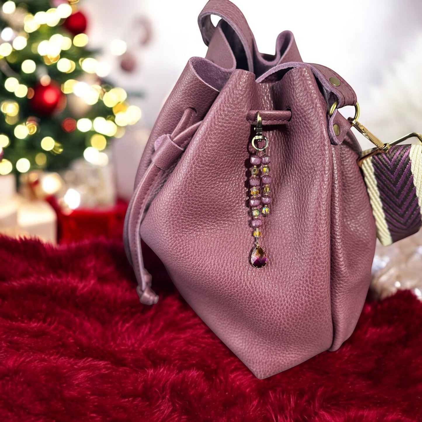 Rhea Artistry Studio elegant beaded keychain with teardrop pendant and brass accents on a dusty rose leather bag.