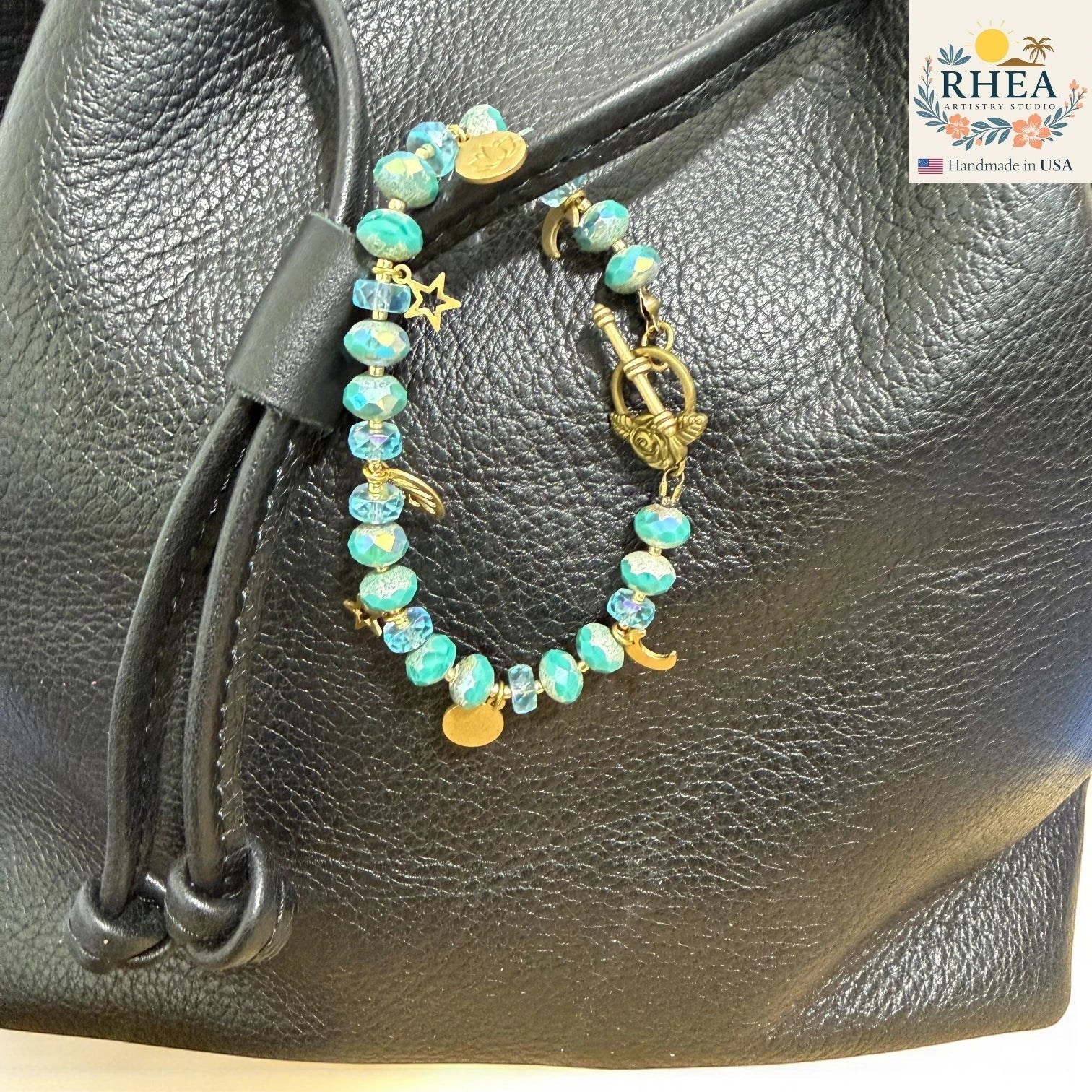 Rhea Artistry Studio handmade beaded purse charm with Czech glass beads in aqua and blue, featuring brass moon, star, and lotus charms.