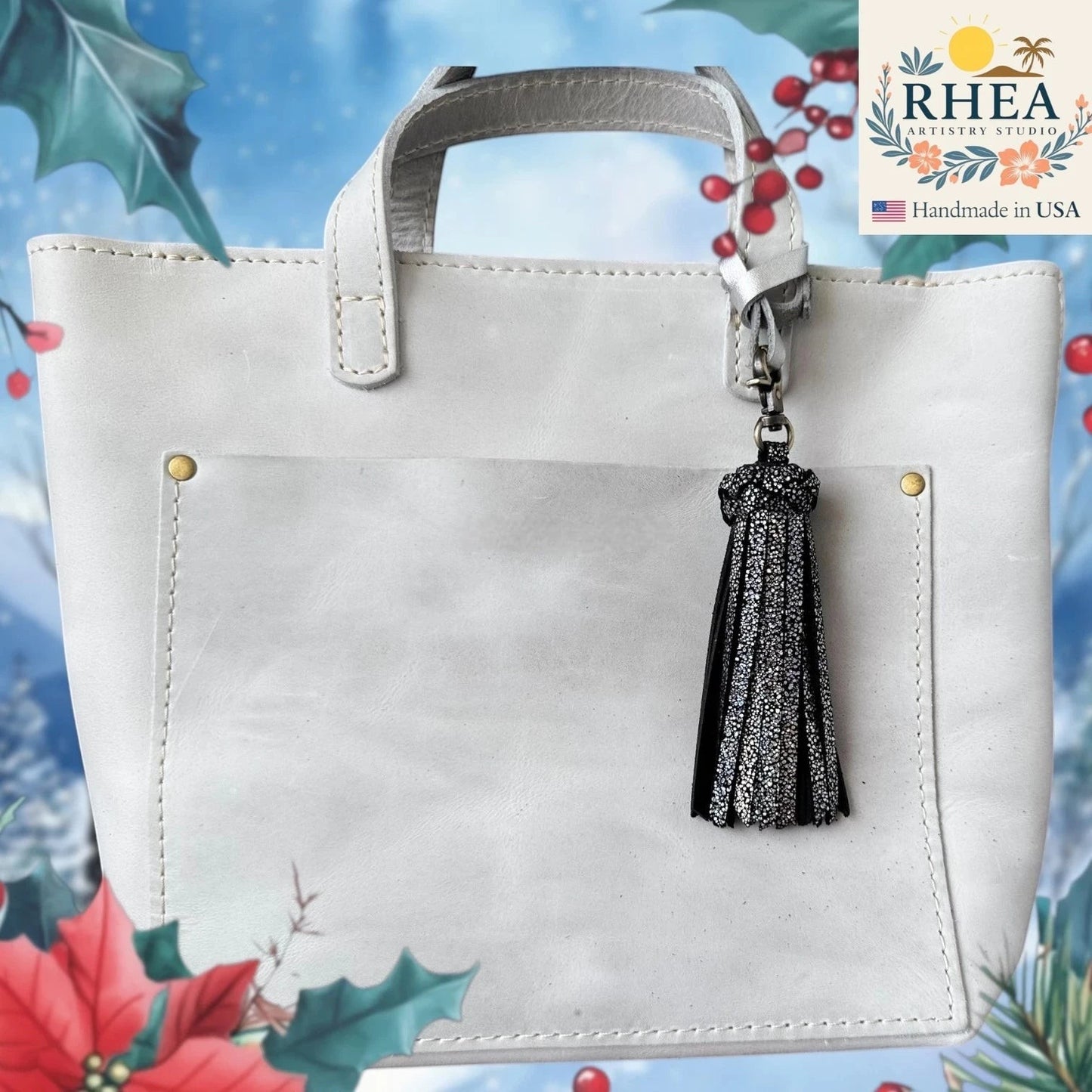 Rhea Artistry Studio handmade black leather tassel bag charm with silver glitter accents and lobster clasp.