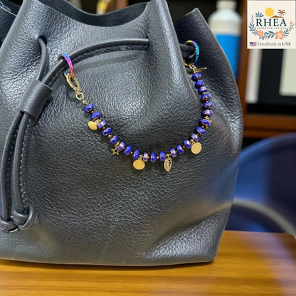 Rhea Artistry Studio handmade beaded purse charm with blue Czech glass beads and brass celestial charms: moon, star, leaf.