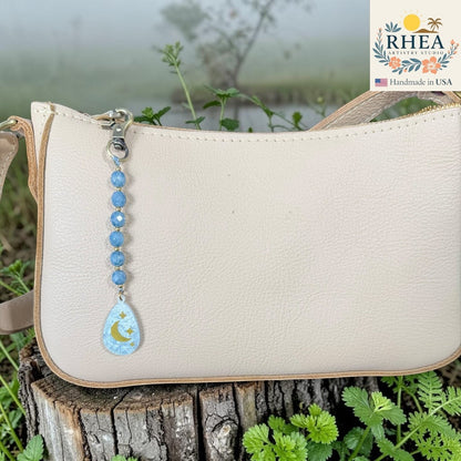 Rhea Artistry Studio blue multi-faceted glass bead bag charm with engraved moon and stars pendant