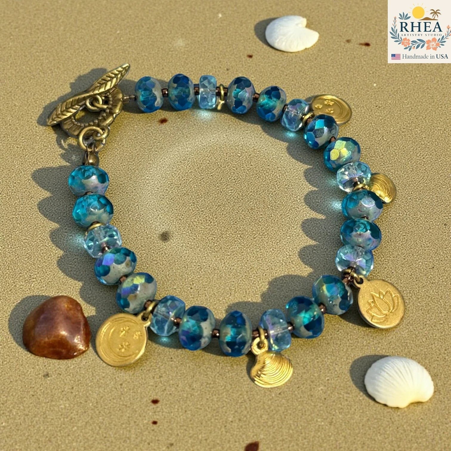 Rhea Artistry Studio handmade blue glass bead bracelet with celestial charms and floral toggle clasp.