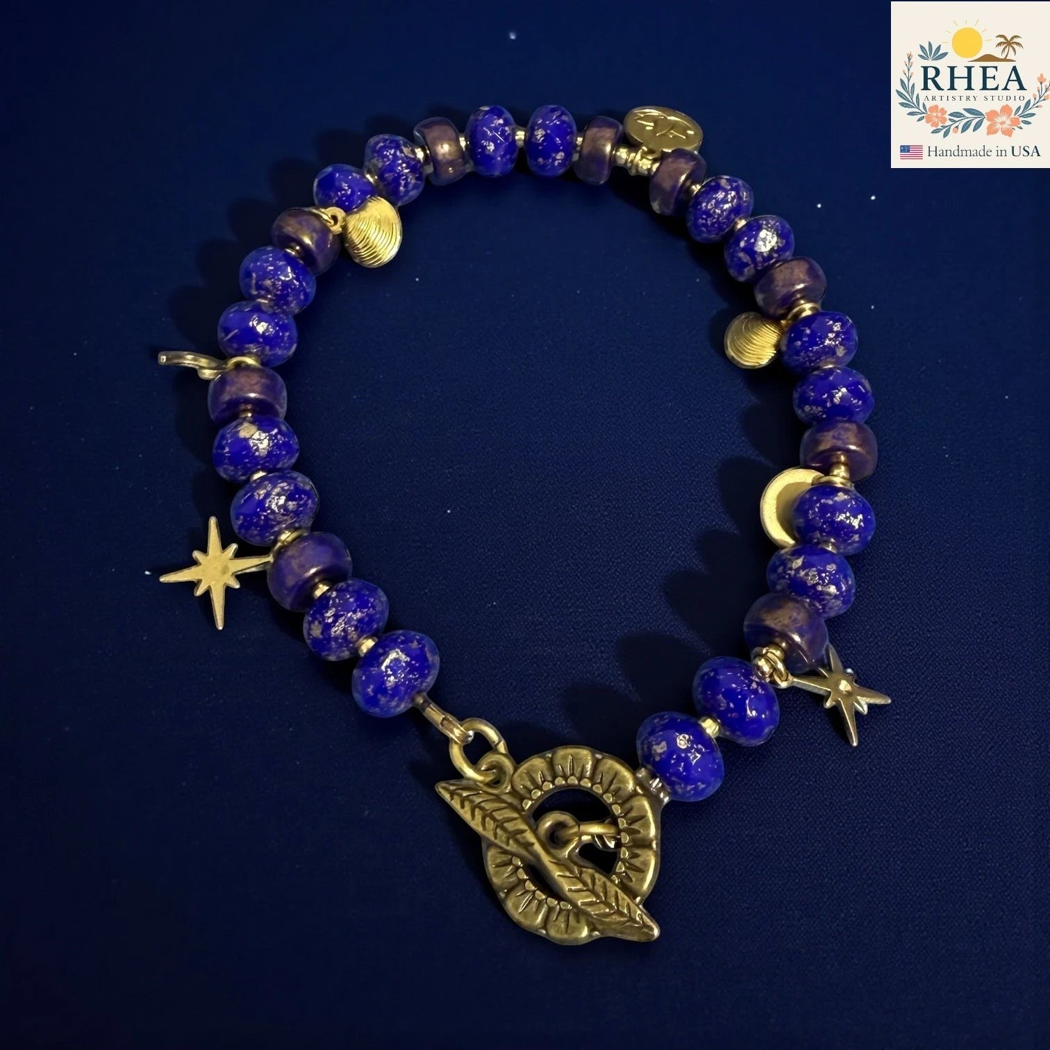 Rhea Artistry Studio handmade celestial bracelet with blue glass beads, brass star and moon charms, and floral toggle clasp.