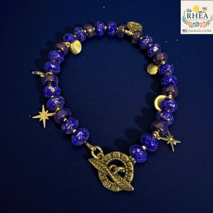 Rhea Artistry Studio handmade celestial bracelet with blue glass beads, brass star and moon charms, and floral toggle clasp.