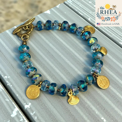 Rhea Artistry Studio handmade blue glass bead bracelet with celestial charms and floral toggle clasp.