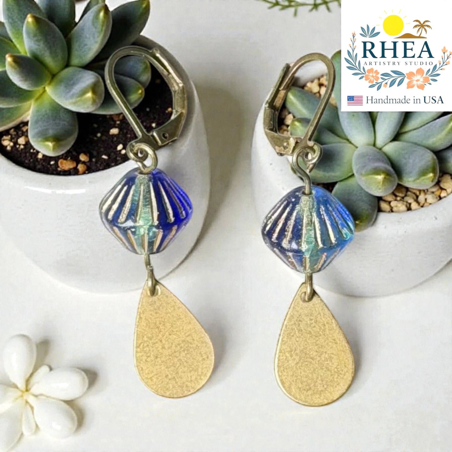 Rhea Artistry Studio blue faceted glass bead drop earrings with brushed brass teardrop charm, 2 inches long.