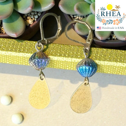 Rhea Artistry Studio handcrafted drop earrings with faceted blue glass beads and brushed brass teardrop charms, 2 inches long.