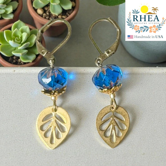 Rhea Artistry Studio blue faceted glass bead and brass leaf drop earrings, approx. 2 inches long, with leverback closures.
