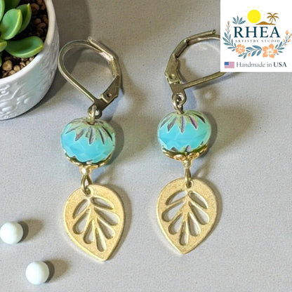 Rhea Artistry Studio blue faceted glass bead and brass leaf drop earrings, approx. 2 inches long, with leverback closures.