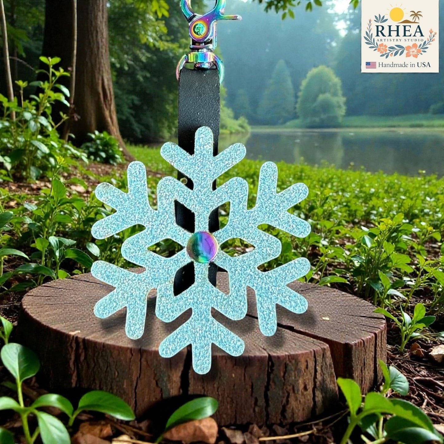 Rhea Artistry Studio light blue glitter snowflake charm with iridescent center, handmade leather bag accessory.