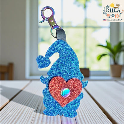 Rhea Artistry Studio blue glitter leather gnome bag charm with red heart detail and rainbow clasp.