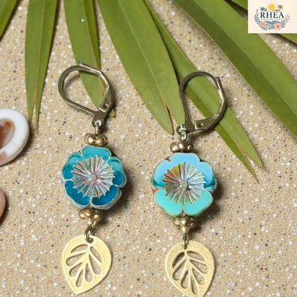 Rhea Artistry Studio blue and teal hibiscus glass drop earrings with gold leaf charms and lever back hooks.