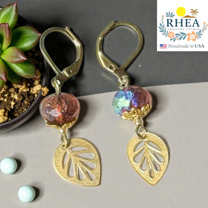 Rhea Artistry Studio handcrafted brass leaf drop earrings with faceted glass beads in pink and iridescent blue. Approx. 2 inches long.
