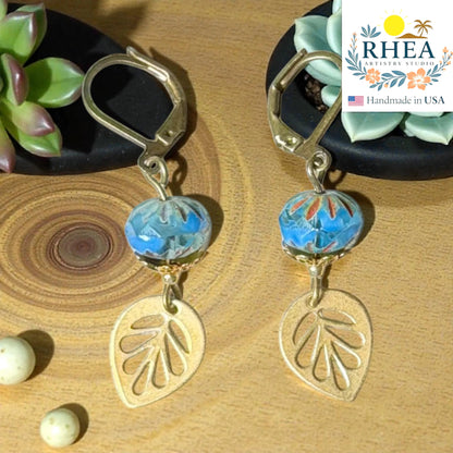 Rhea Artistry Studio blue faceted glass bead and brass leaf drop earrings, approx. 2 inches long, with leverback closures.
