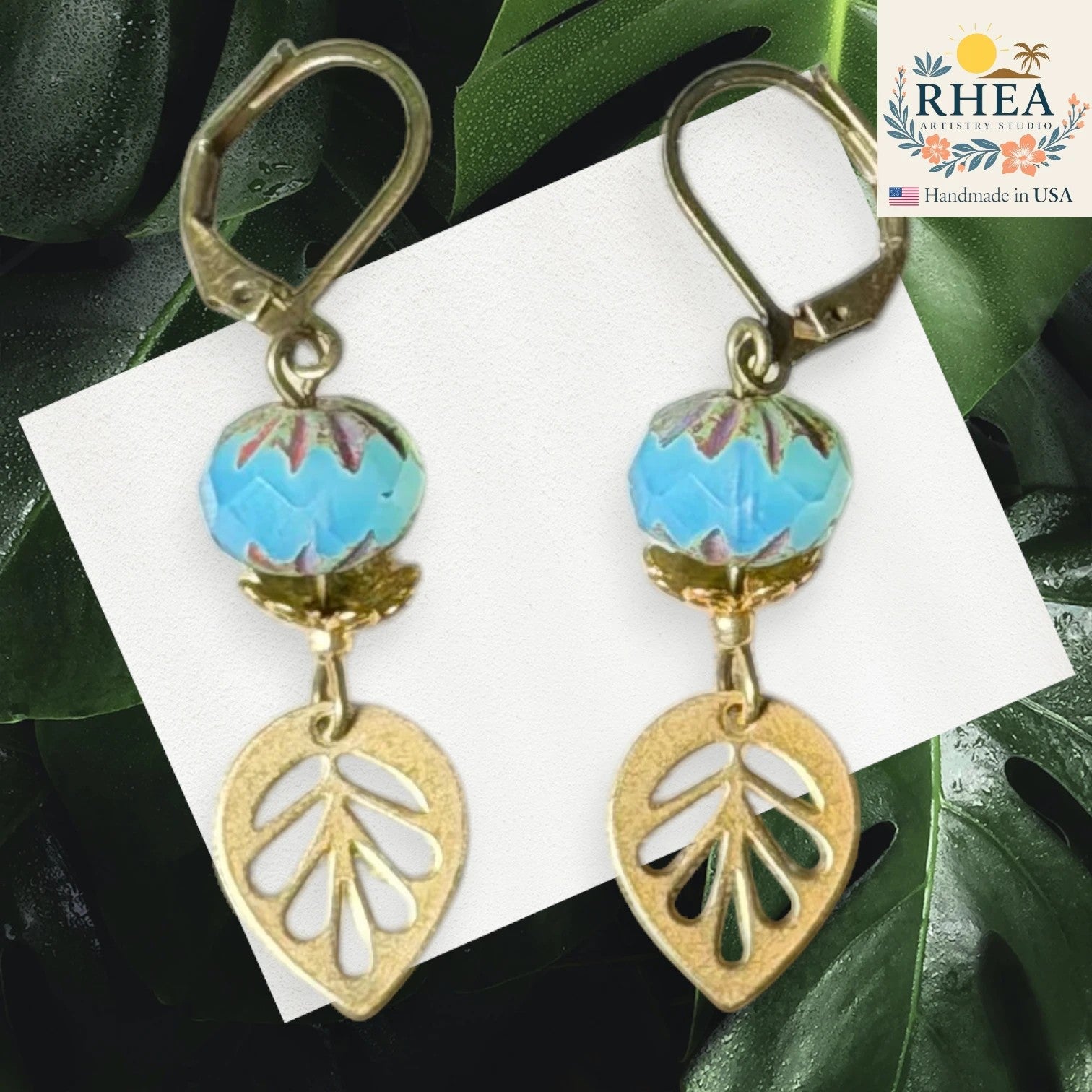 Rhea Artistry Studio blue faceted glass bead and brass leaf drop earrings, approx. 2 inches long.
