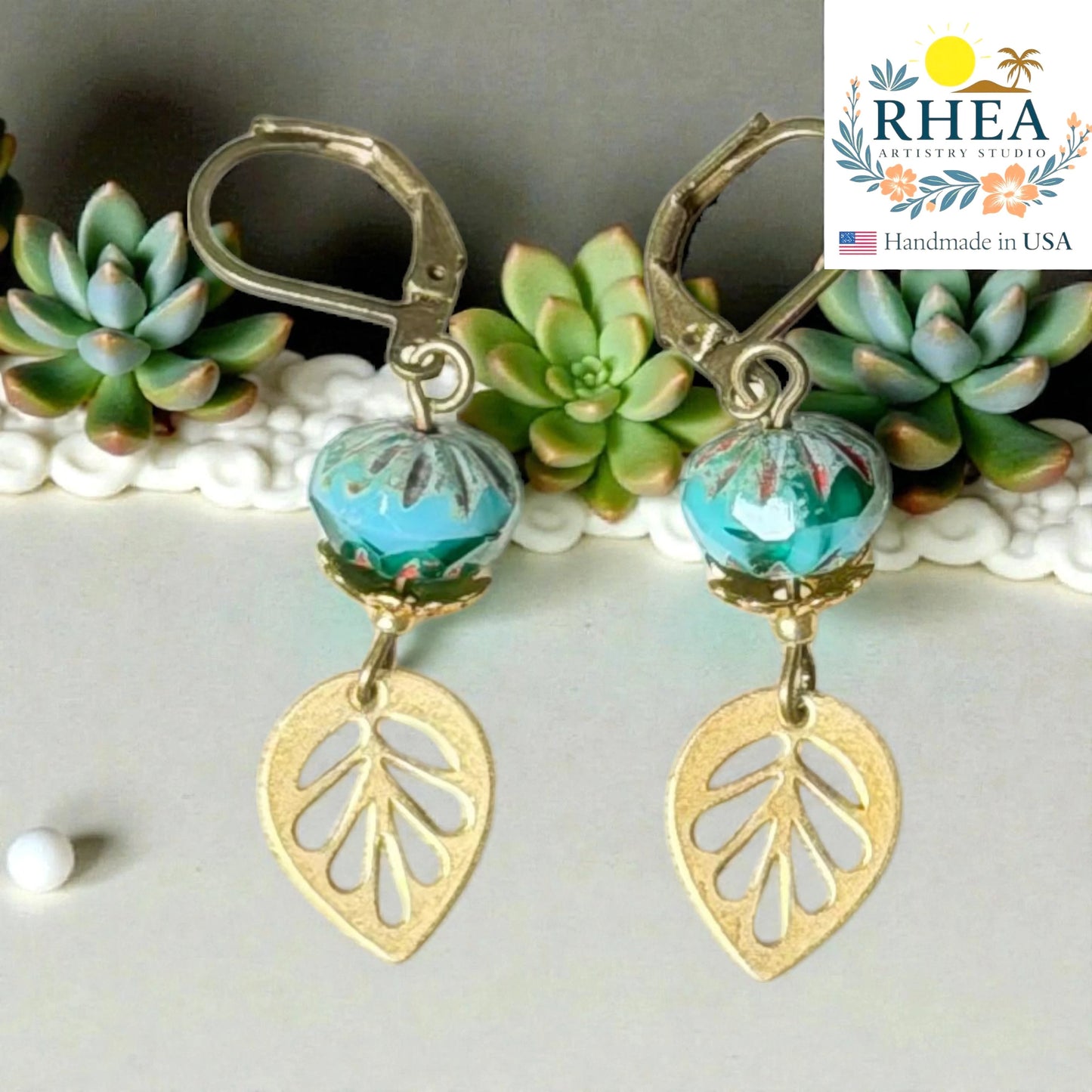 Rhea Artistry Studio handcrafted brass leaf drop earrings with blue faceted glass beads, 2 inches long, leverback closure.