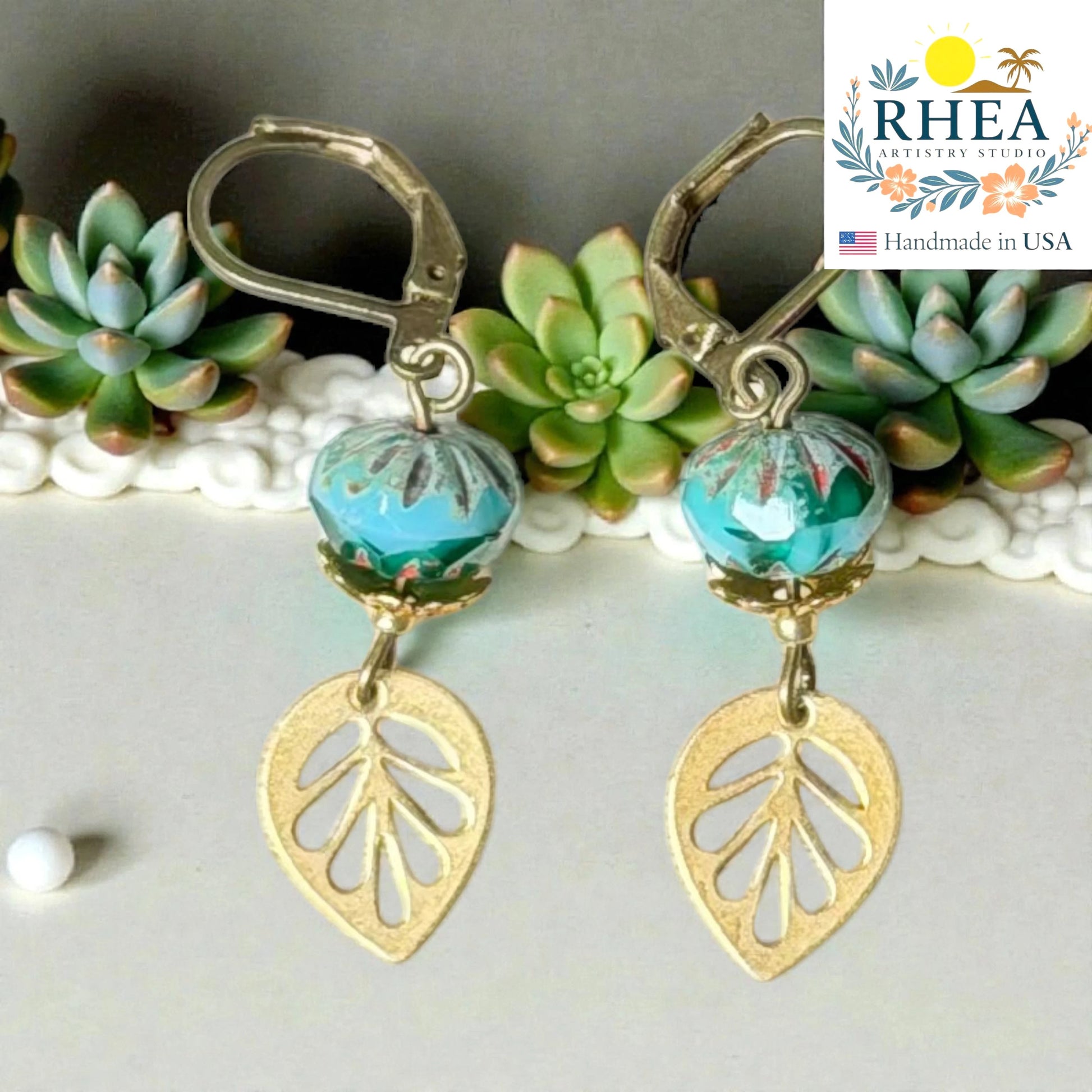 Rhea Artistry Studio handcrafted brass leaf drop earrings with blue faceted glass beads, 2 inches long, leverback closure.