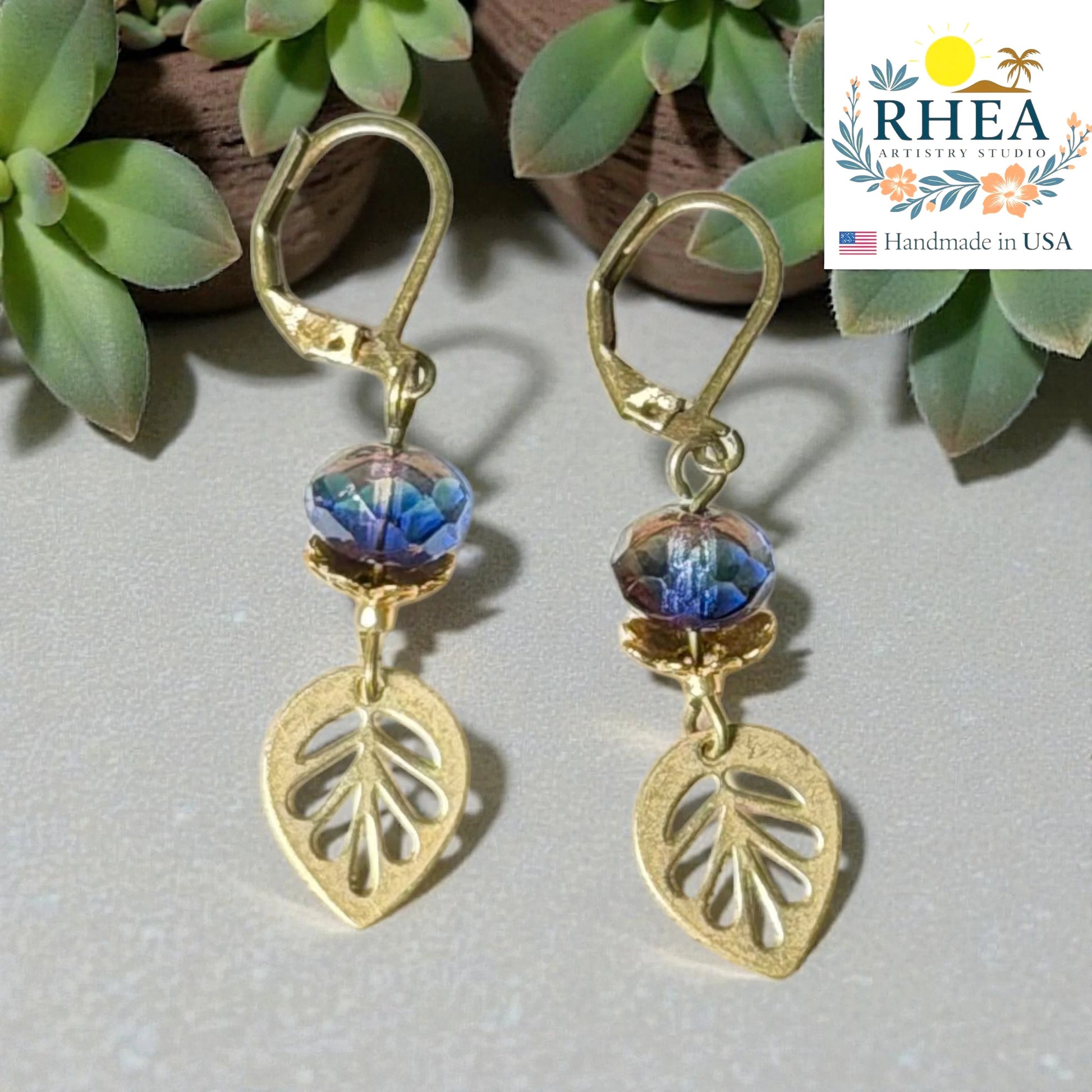 Rhea Artistry Studio brass leaf drop earrings with faceted blue and purple glass beads, 2 inches long.