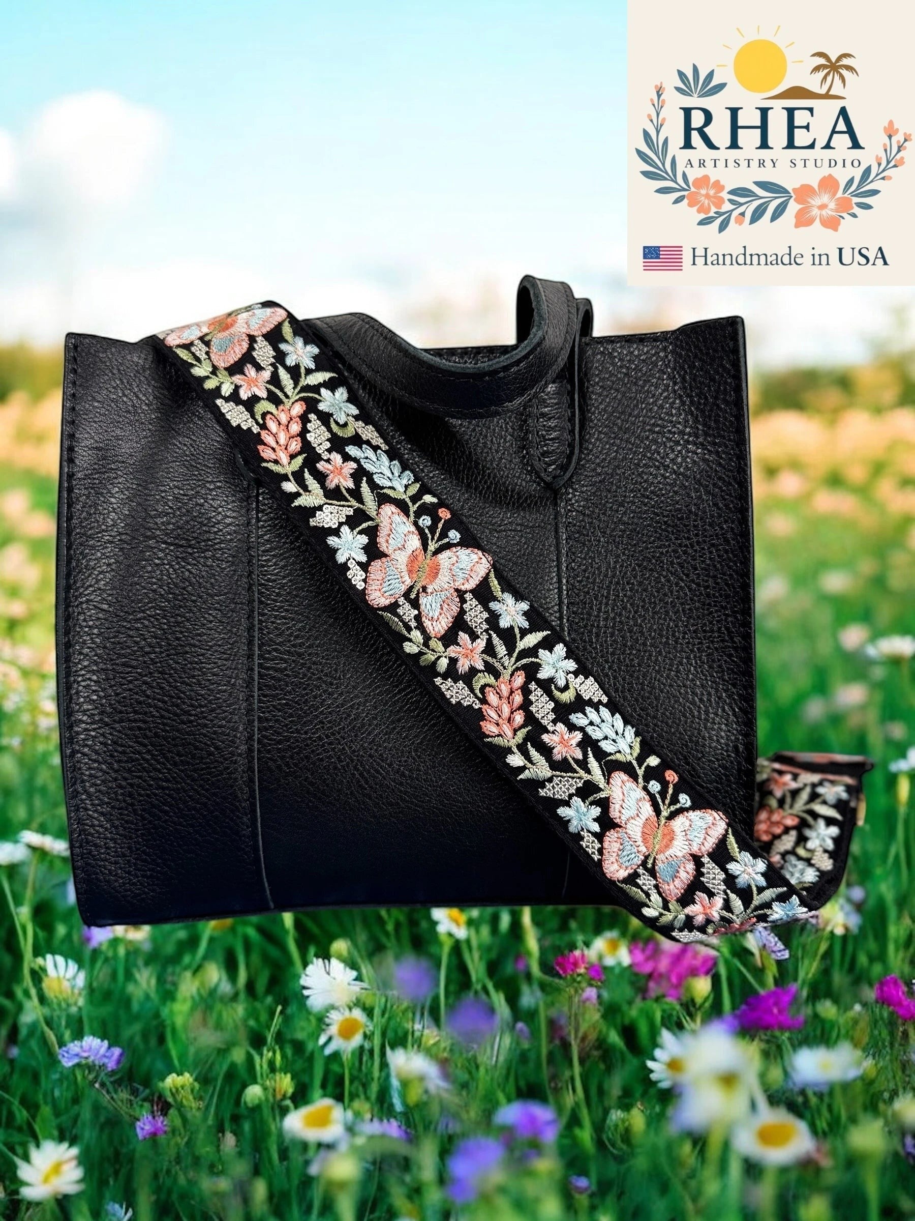 Rhea Artistry Studio black crossbody strap with colorful butterfly and floral embroidery, 2-inch wide, adjustable length, brushed brass hardware.