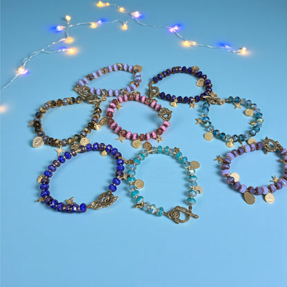 Rhea Artistry Studio handmade glass bead bracelets in various colors like purple, pink, blue, and bronze, featuring celestial charms and floral toggle clasps.