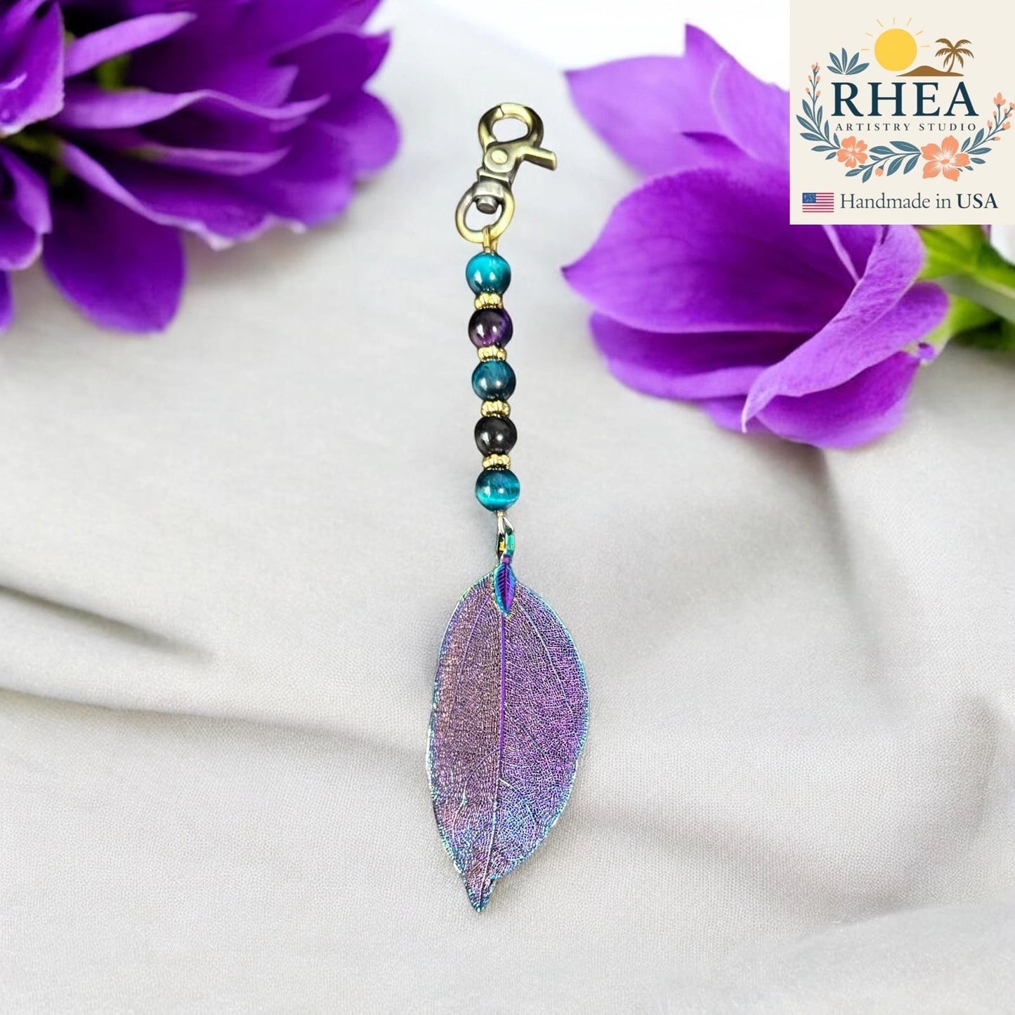 Rhea Artistry Studio Celestial Cascade bag charm with iridescent leaf pendant and galaxy gemstone beads, antique bronze clasp.