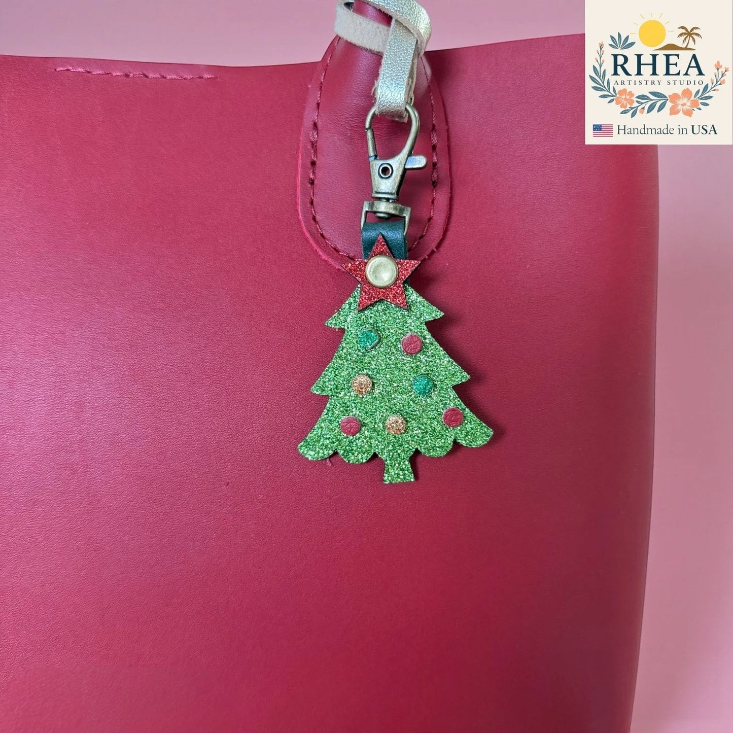 Rhea Artistry Studio green glitter Christmas tree charm with red and gold ornaments and a red star topper, attached to a red bag.