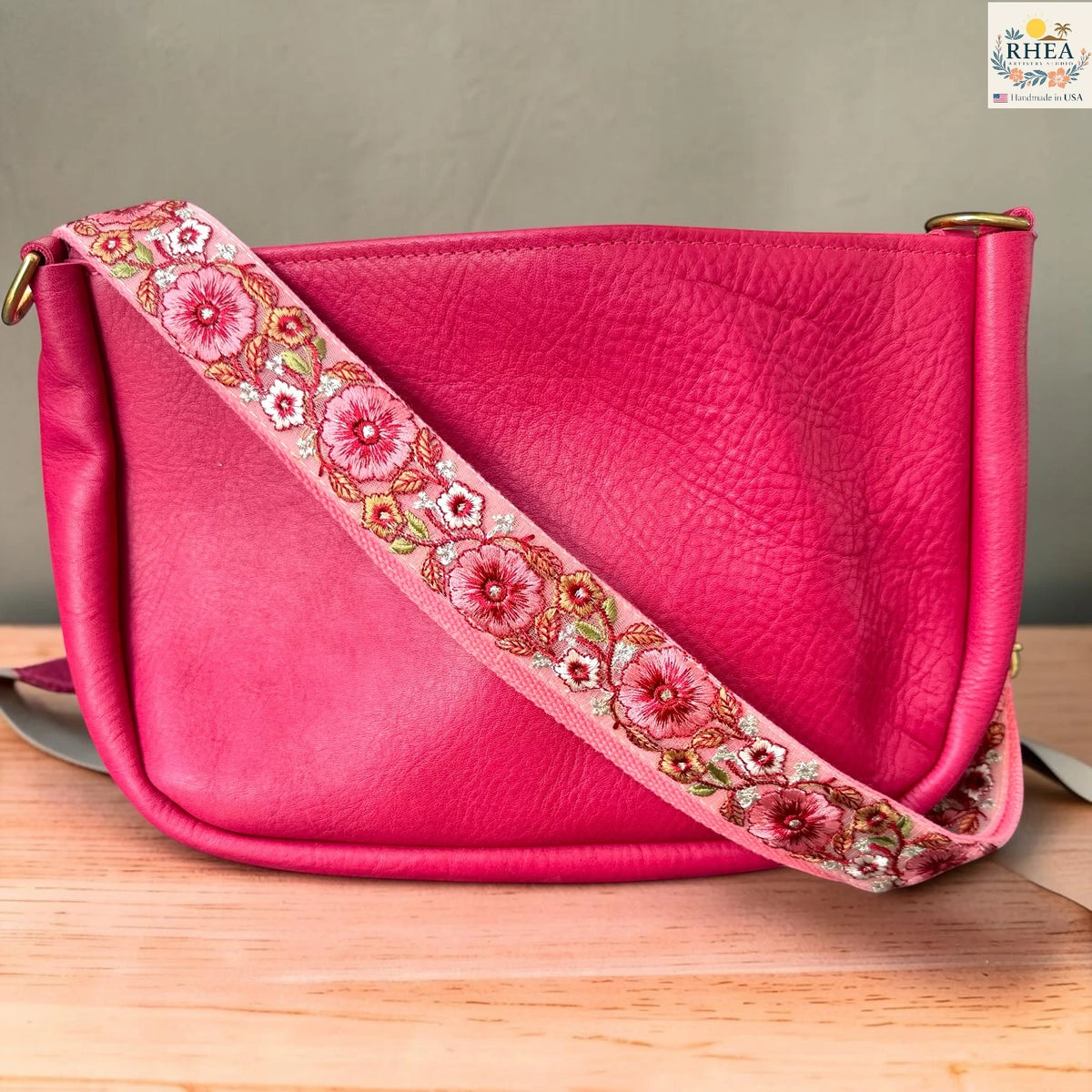 Rhea Artistry Studio ivory crossbody strap with coral and red floral embroidery with green leaf accents, 1.5-inch width, adjustable length.