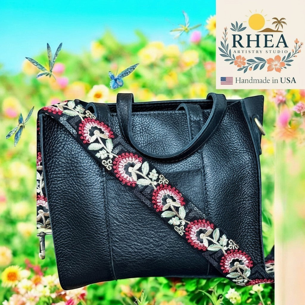 Rhea Artistry Studio black leather handbag with a 2-inch wide crimson tapestry embroidered strap featuring floral motifs and adjustable length.