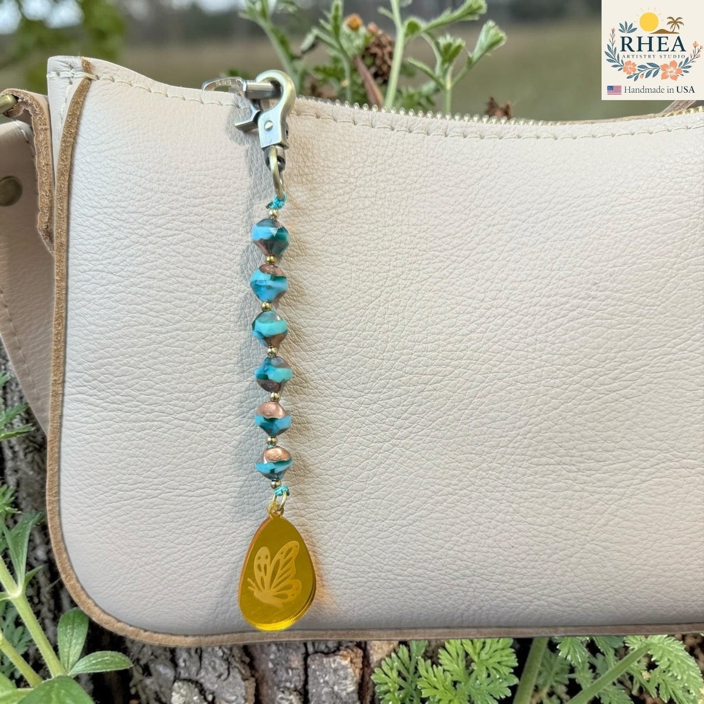 Rhea Artistry Studio artisan bag charm with Czech glass beads, brass accents, and a hand-painted yellow pendant featuring a butterfly design.