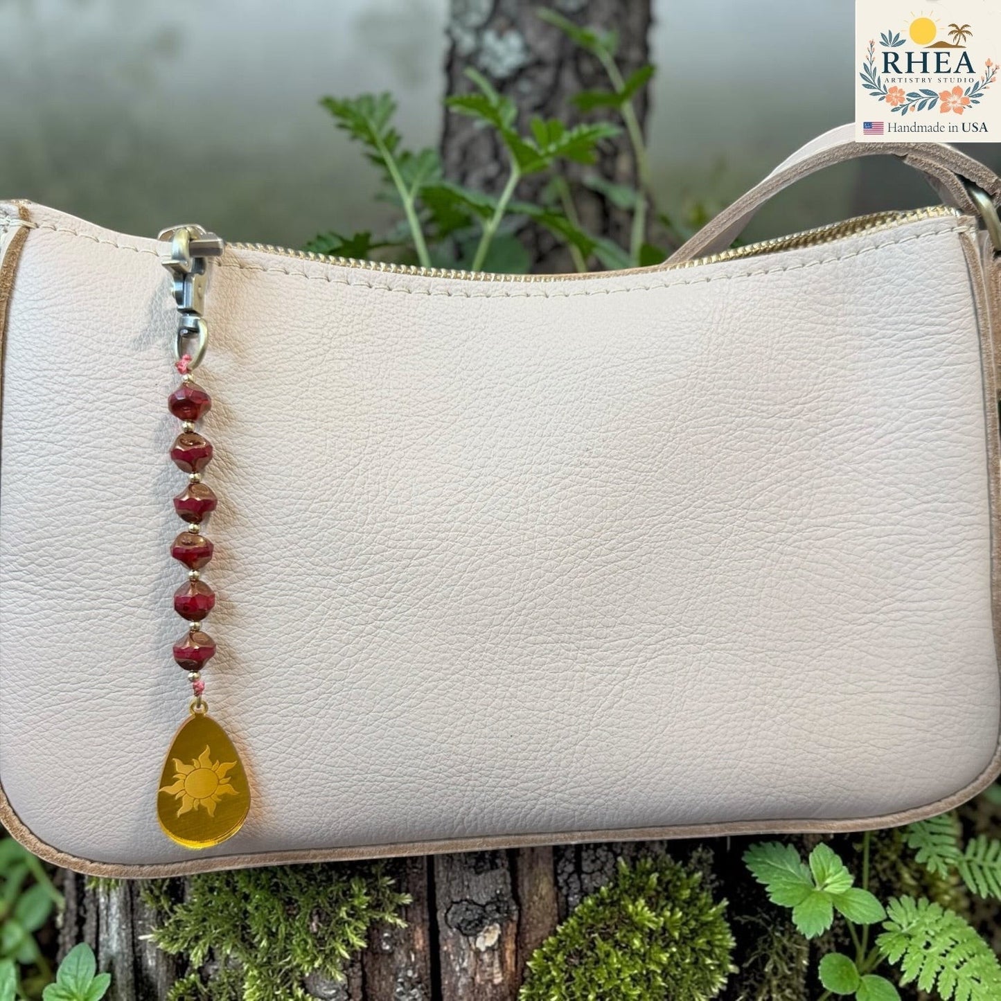 Rhea Artistry Studio artisan bag charm with red Czech glass beads, brass accents, and a hand-painted yellow sun pendant.