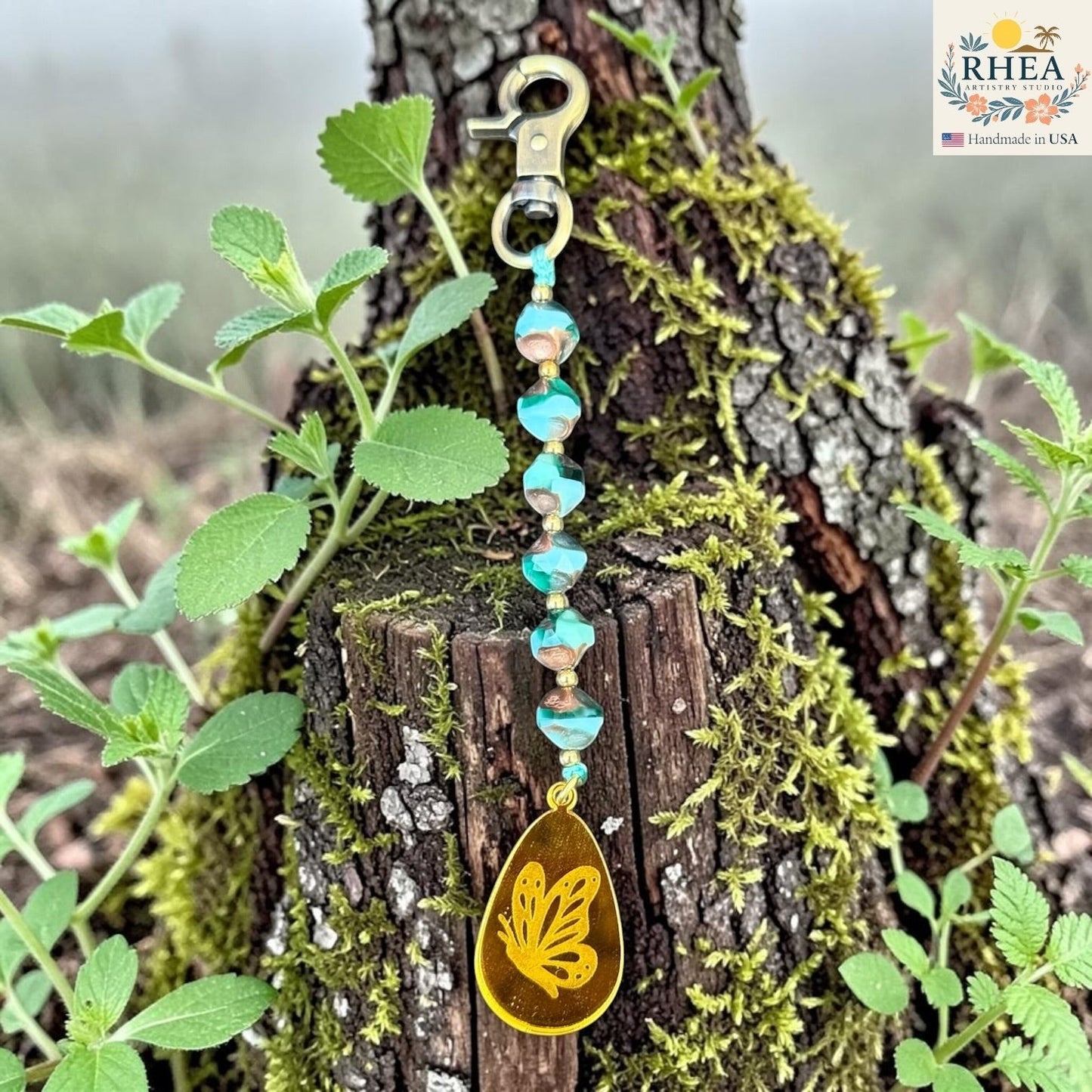 Rhea Artistry Studio artisan bag charm with blue Czech glass beads, brass accents, and a hand-painted yellow butterfly pendant.