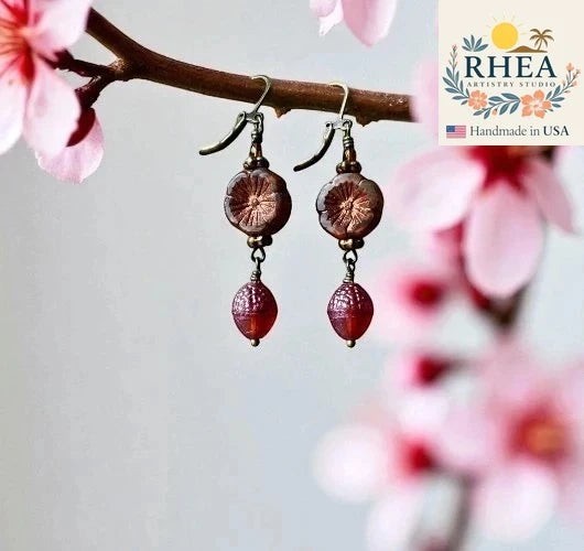 Rhea Artistry Studio handmade Czech glass earrings with rusty pink floral beads and brick orange acorn charms, brass hardware, 1.5-2 inches long.