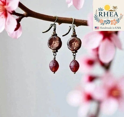 Rhea Artistry Studio handmade Czech glass earrings with rusty pink floral beads and brick orange acorn charms, brass hardware, 1.5-2 inches long.