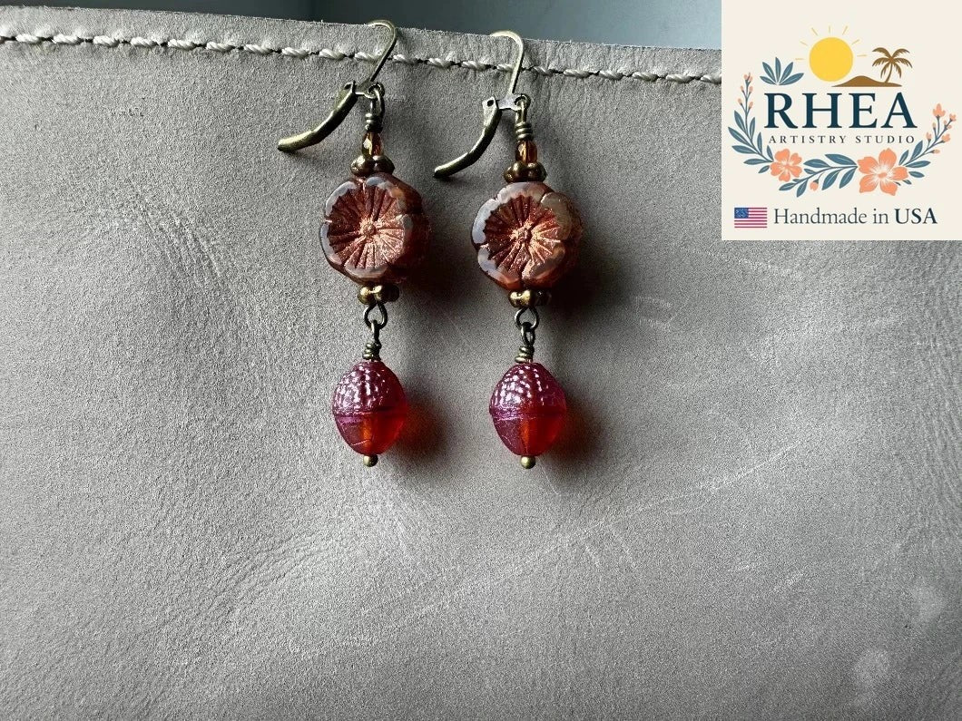 Rhea Artistry Studio handmade Czech glass earrings with rusty pink floral beads and brick orange acorn charms, brass hardware, 1.5-2 inches long.