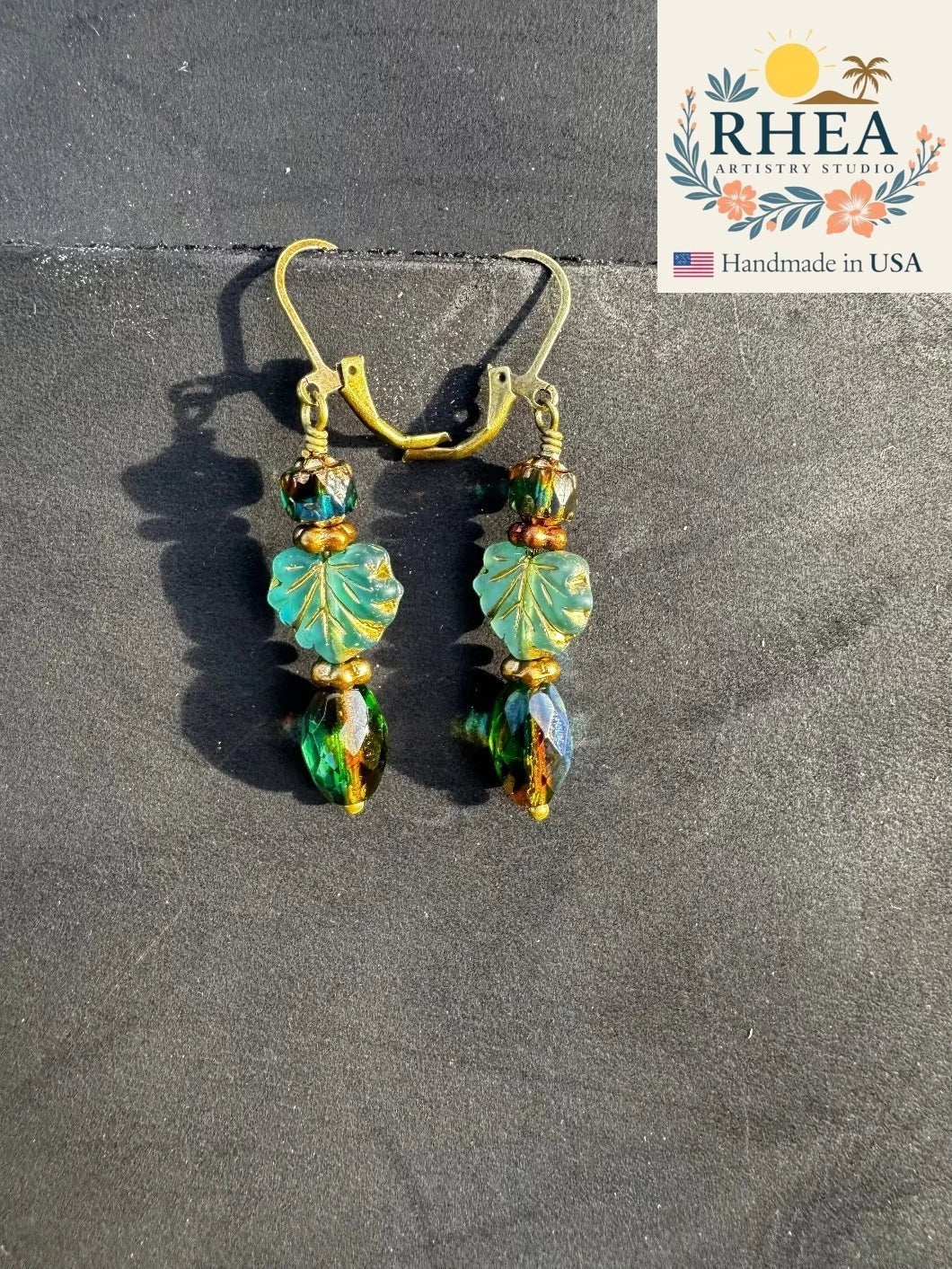 Rhea Artistry Studio handmade Czech glass earrings with teal leaf beads and green faceted beads, brass hardware, 2 inches long.