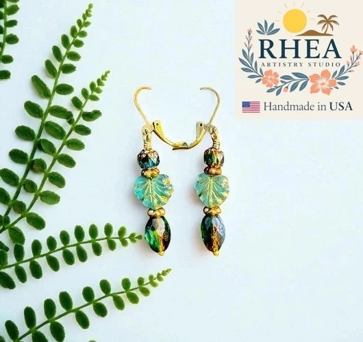 Rhea Artistry Studio handmade Czech glass earrings with green leaf beads and faceted emerald drops, brass hardware, 2 inches long.