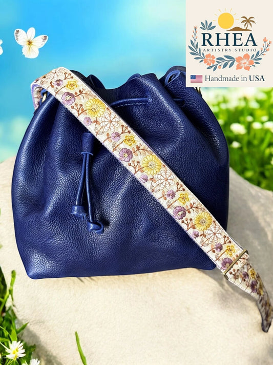 Rhea Artistry Studio embroidered fabric crossbody strap with daisies, adjustable length, and brass hardware.