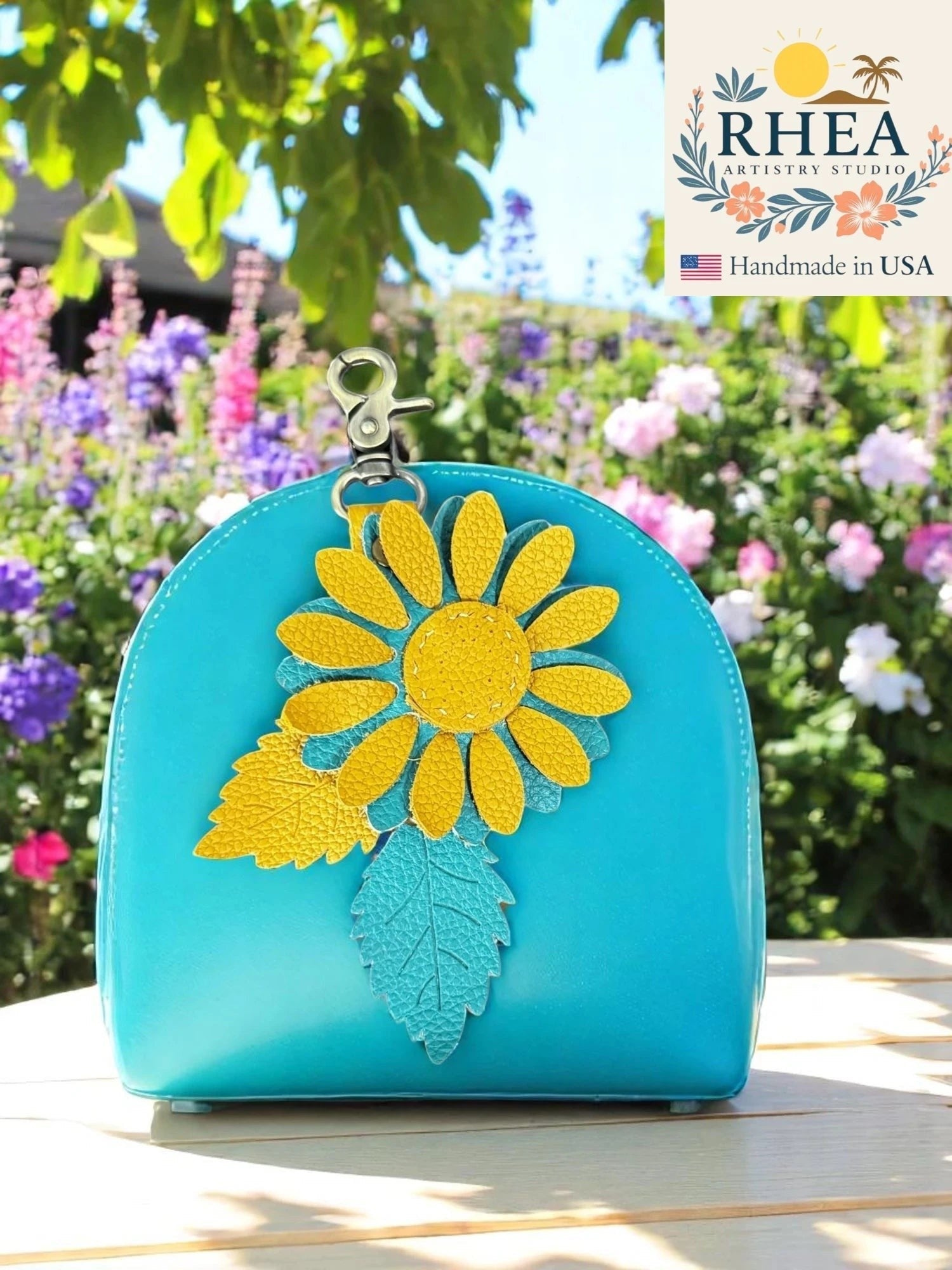 Rhea Artistry Studio turquoise leather pouch with yellow daisy and teal leaf charm, lobster clasp, handmade in USA.