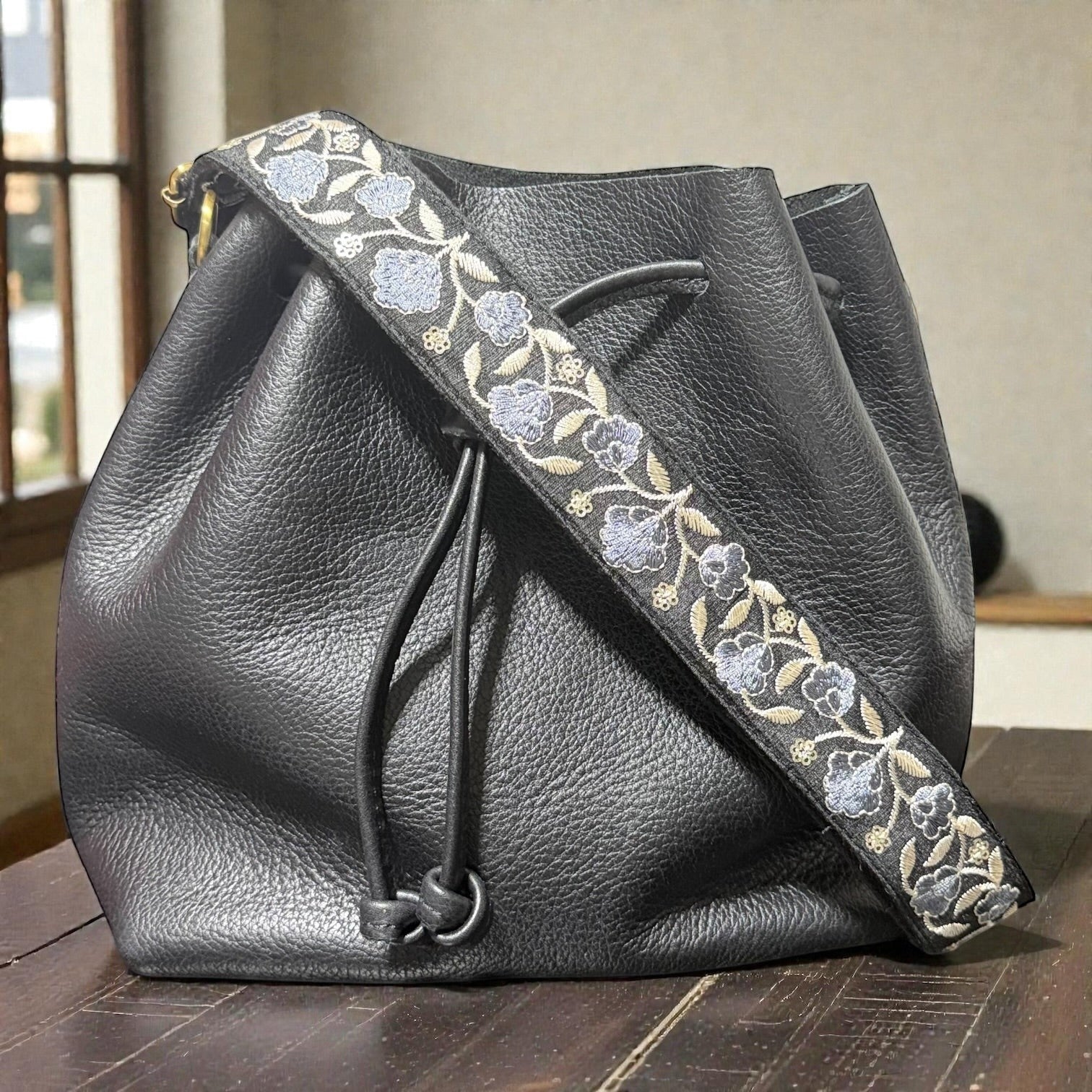 Rhea Artistry Studio Sierra Bloom embroidered crossbody strap with blue floral pattern on cotton webbing, 1.5-inch wide, adjustable 30-54 inches.