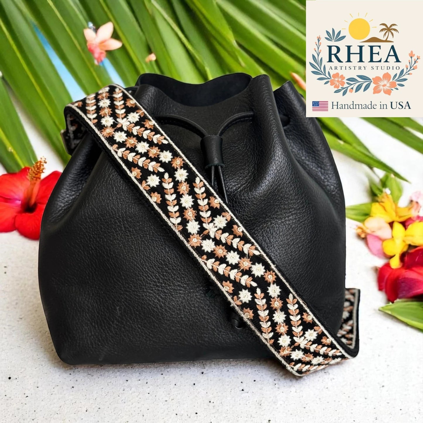 Rhea Artistry Studio 2-inch crossbody strap with desert petal embroidery in dusty blue, white, and bronze. Adjustable strap with brushed brass hooks.