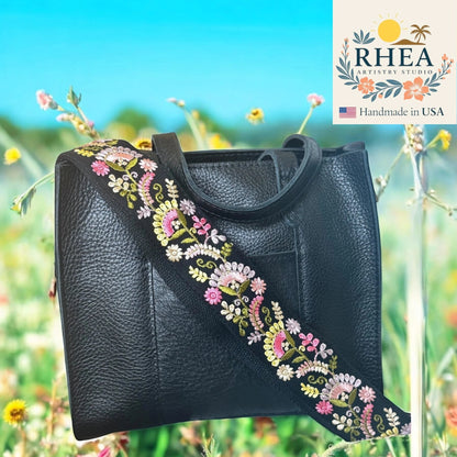 Rhea Artistry Studio black crossbody strap with colorful floral embroidery and brushed brass hardware.
