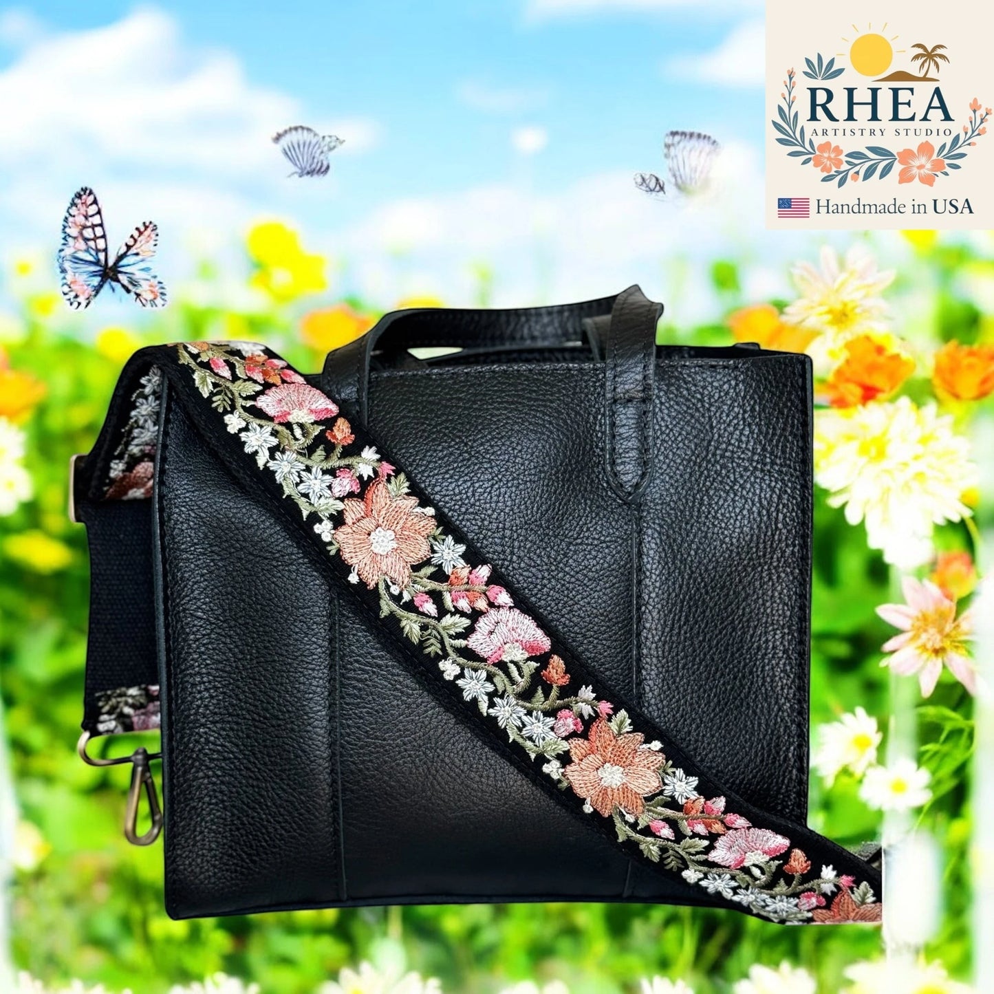 Rhea Artistry Studio black leather tote bag with a 2-inch wide embroidered strap featuring pink and white floral patterns.