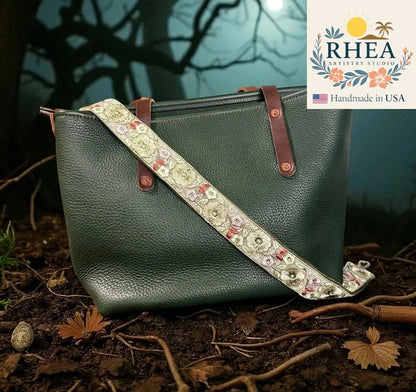 Rhea Artistry Studio 1.5-inch adjustable crossbody strap with embroidered floral pattern in cream, pink, and red on cotton webbing.