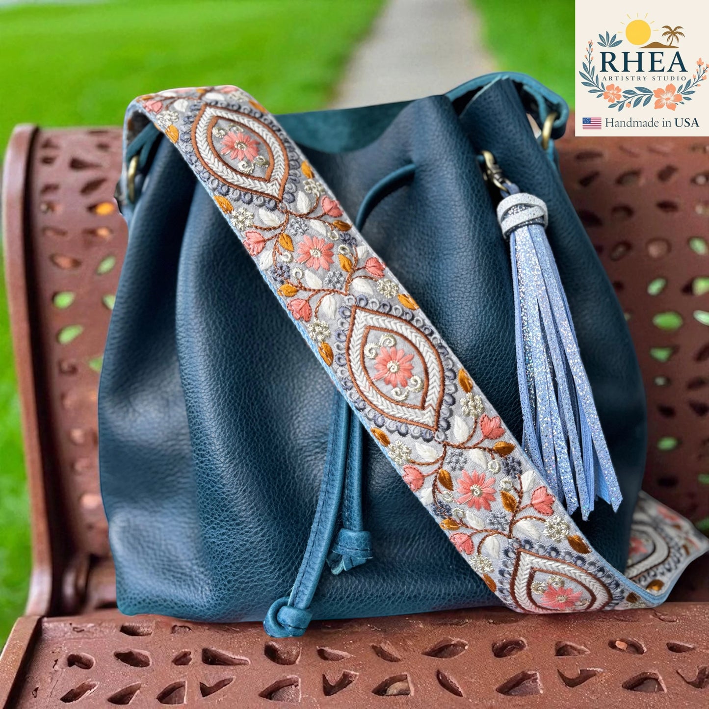 Rhea Artistry Studio 2-inch wide crossbody strap with embroidered floral panels and geometric frames, featuring coral pink flowers and grey backing.